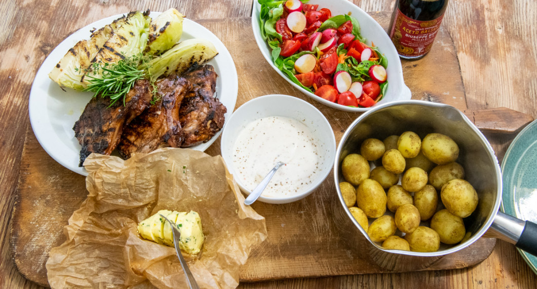 Du kan servera kotletterna med valfria tillbehör. Ovan med vitlökssmör, grillad spetskål, kall sås av gräddfil och sweet chili, sallad samt kokt färskpotatis. 