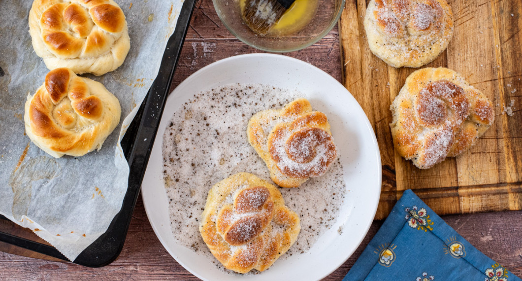 När bullarna svalnat något så penslar de dem med smält smör och vänder i socker blandat med stött kardemumma. 