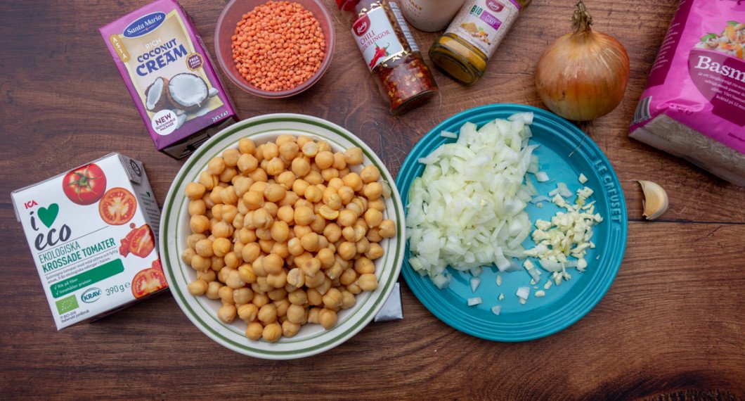 Några av ingredienserna till kikärtsgrytan: krossade tomater, kokta kikärtor, kokosgrädde, röda linser, chiliflakes, curry, salt, gul lök, vitlök. Samt basmatiris att servera till.