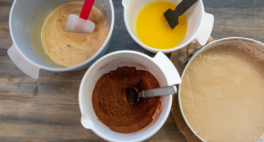 Vispa ihop ägg och socker. Blanda ihop de torra ingredienserna. Smörj en springform med smör och bröa kanterna med hasselnötsmjöl. 