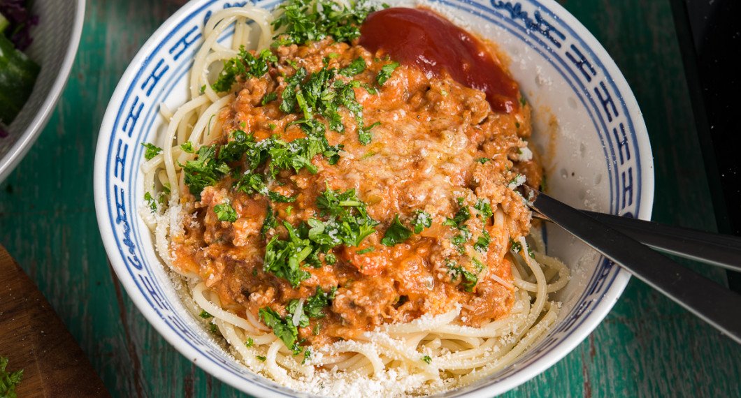 Köttfärssås med spagetti toppad med riven parmesan och hackad persilja samt ketchup vid sidan. 