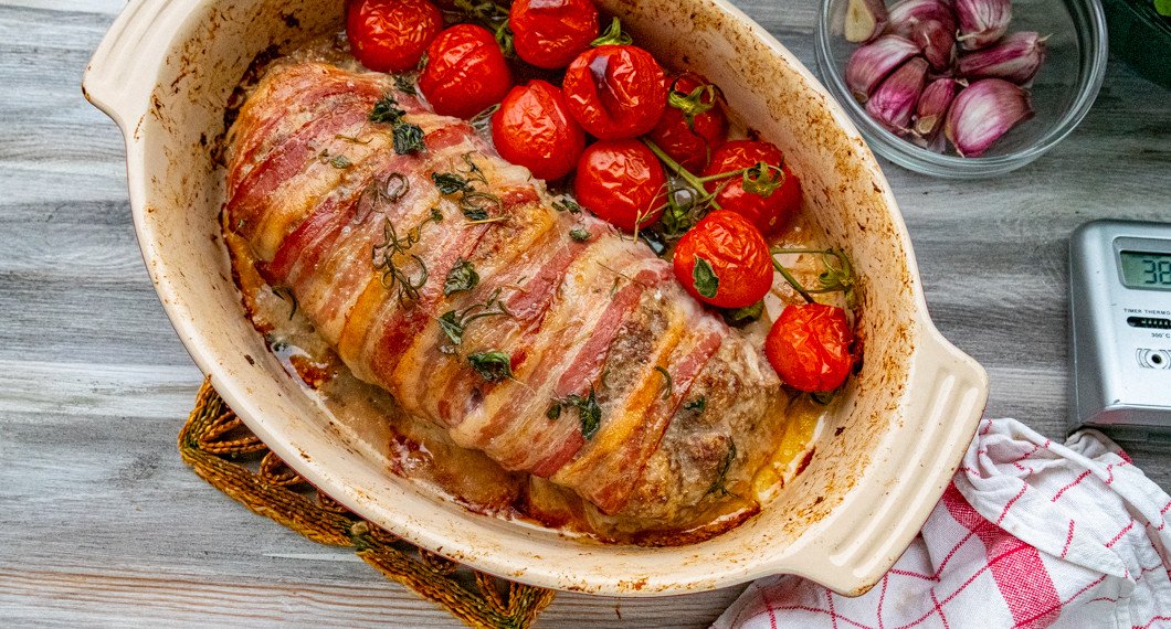 Nylagad lammfärslimpa lindad med bacon och med rostade tomater i ugnsform. 