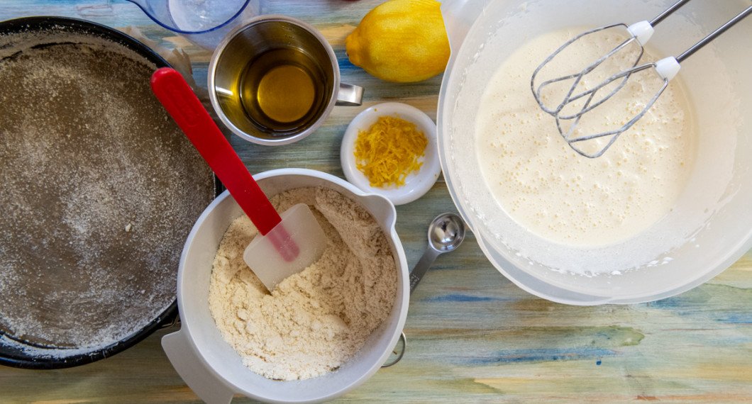 Smörj en rund springform med olivolja och lite mandelmjöl. Blanda mandelmjöl, bakpulver, vetemjöl och salt i en bunke. Vispa ägg och socker fluffigt. Riv skal från citron och pressa ur saft. 