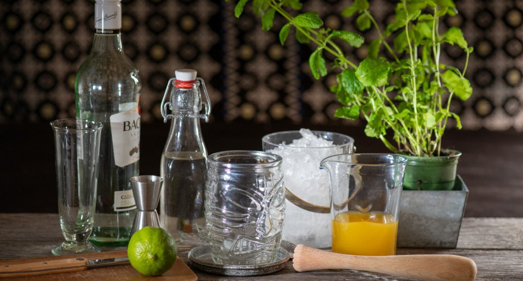 Till drinken behöver du rom, lime, sockerlag, krossad is, mangojuice och mynta. Vidare ett högt glas samt en drinkmortel. 