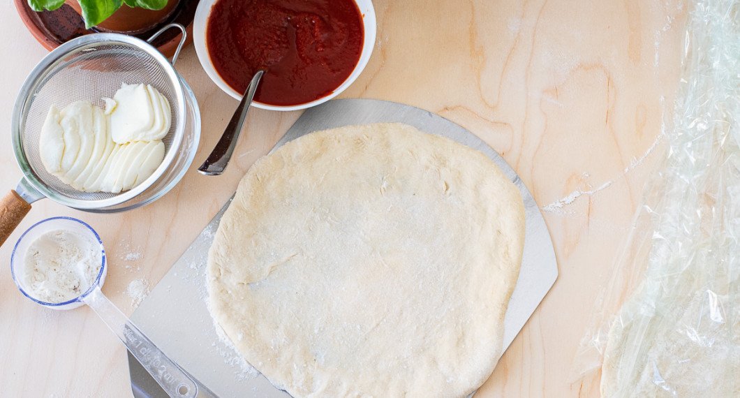 För över pizzabottnen till en mjölad pizzaspade. 