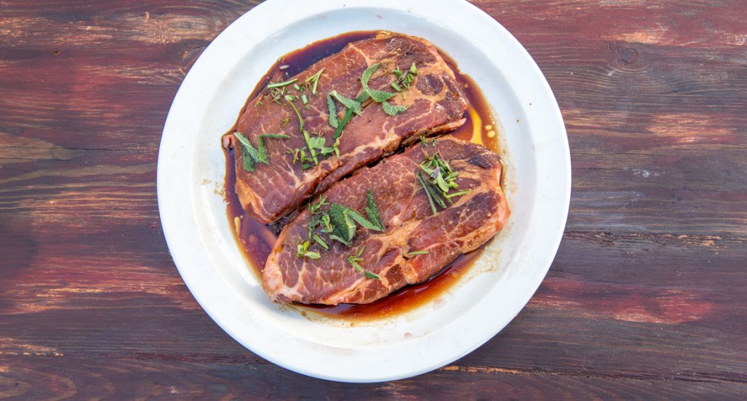 Fläskkarré i marinad redo för grillen toppad med färsk timjan, rosmarin och salvia. 