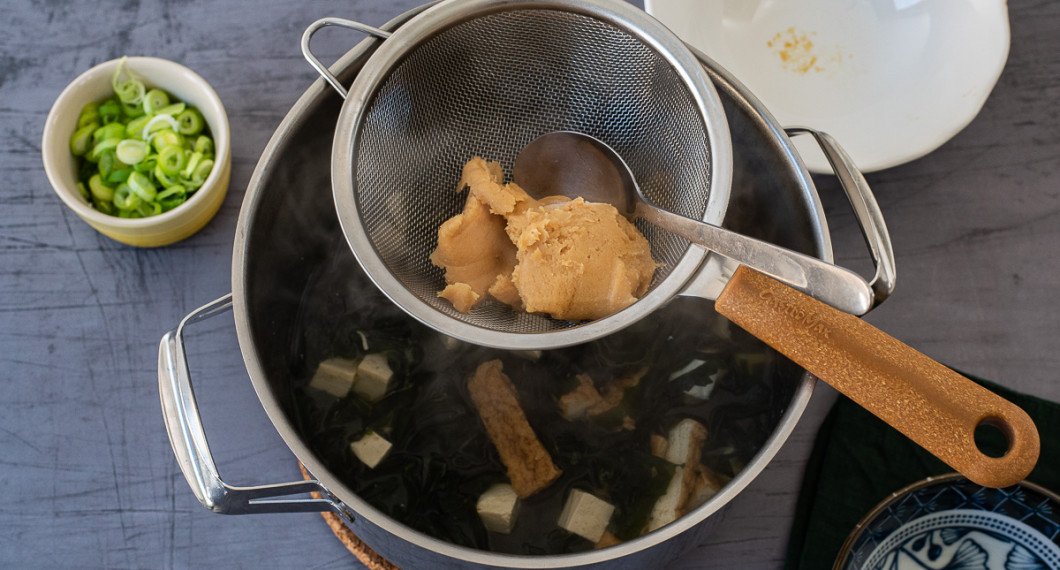 Misopasta trycks genom en sil ner i soppan - detta är mest om misopastan har lite grövre bitar i sig. 