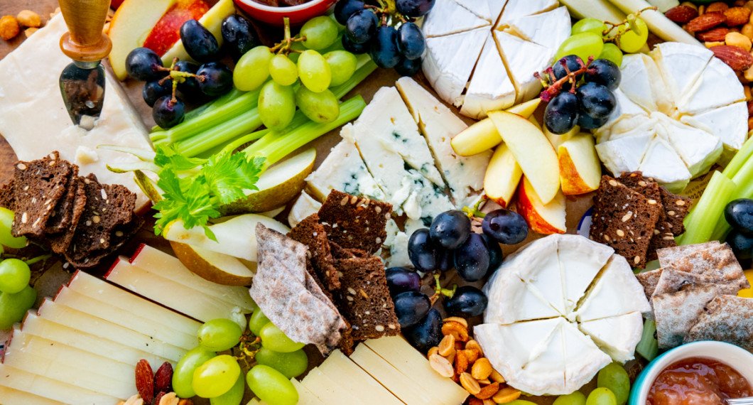 Parmesan med parmesankniv, Pecorino och Gruyère i bitar, i mitten Stilton ädelost, till höger Chèvre samt vitmögelostarna Camembert och Brillat Savarin samt tärnad Cheddarost. 