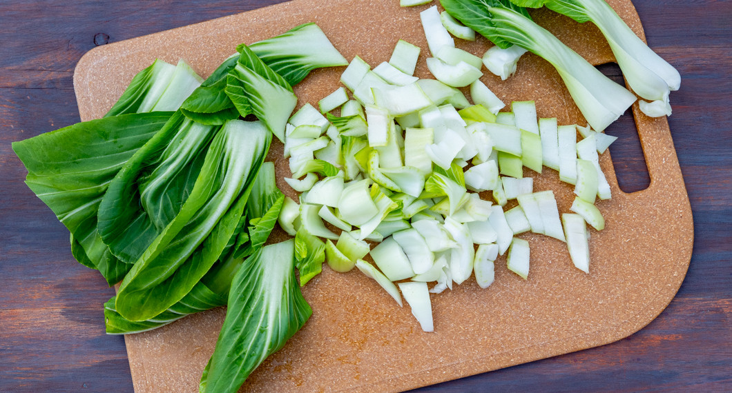 Pak choi som strimlats på en skärbräda. 