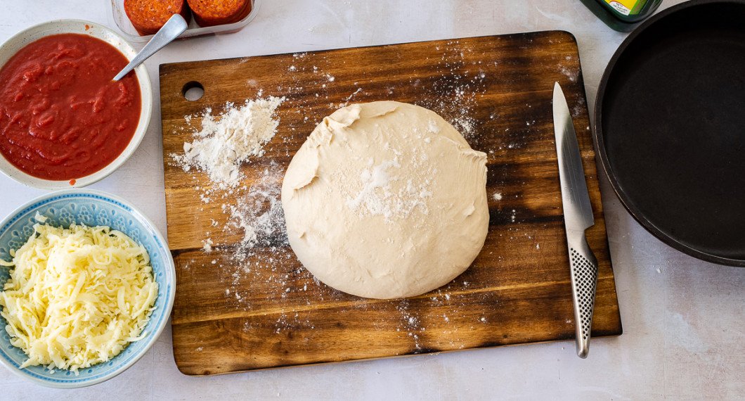 Sätt på ugnen, förbered pålägg och stjälp upp den jästa degen på bakbord eller stor skärbräda. Ta fram en ugnsfast stekpanna och olivolja. 