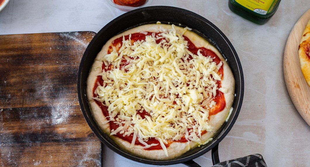 Bred ut pizzasås och fördela över riven ost. 