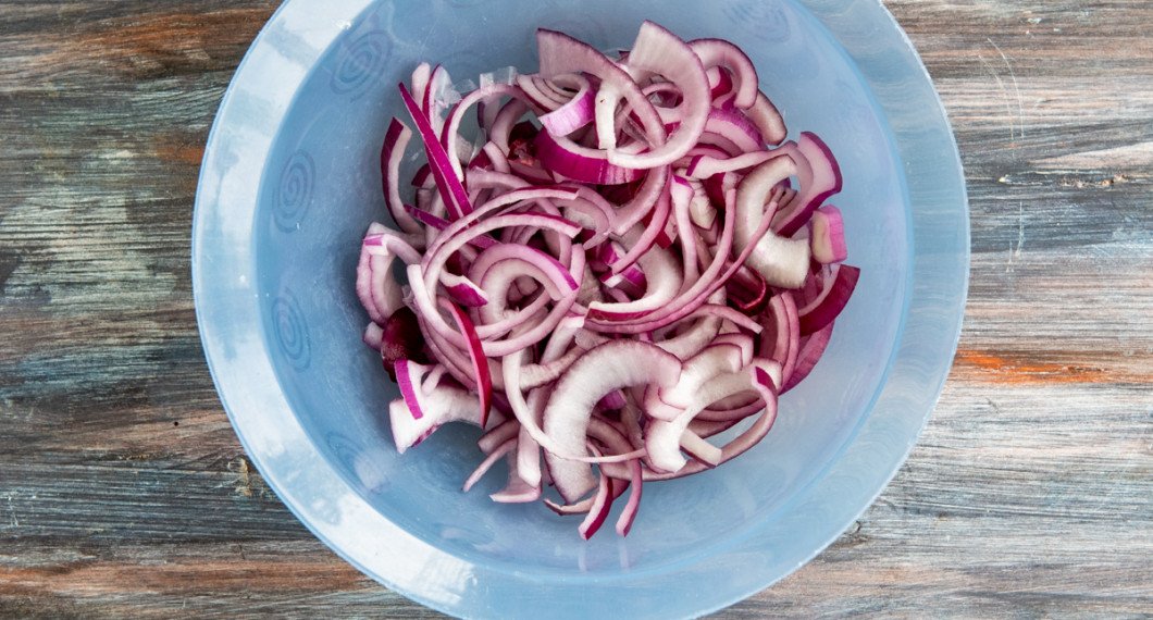 Rödlöken skärs i strimlor och blandas med salt. Arbeta gärna in saltet med händerna så mjuknar löken snabbare. 