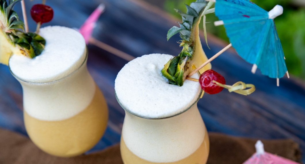 Garneringen av Piña Colada drinkarna med en bit färsk ananas med blad kvar, maraschino körsbär på tandpetare instucken i ananasen samt ett drinkparaply och sugrör. 