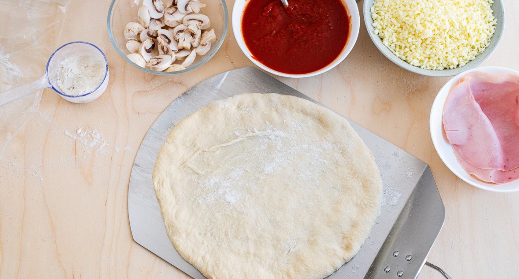 För över pizzabottnen till en mjölad pizzaspade. 