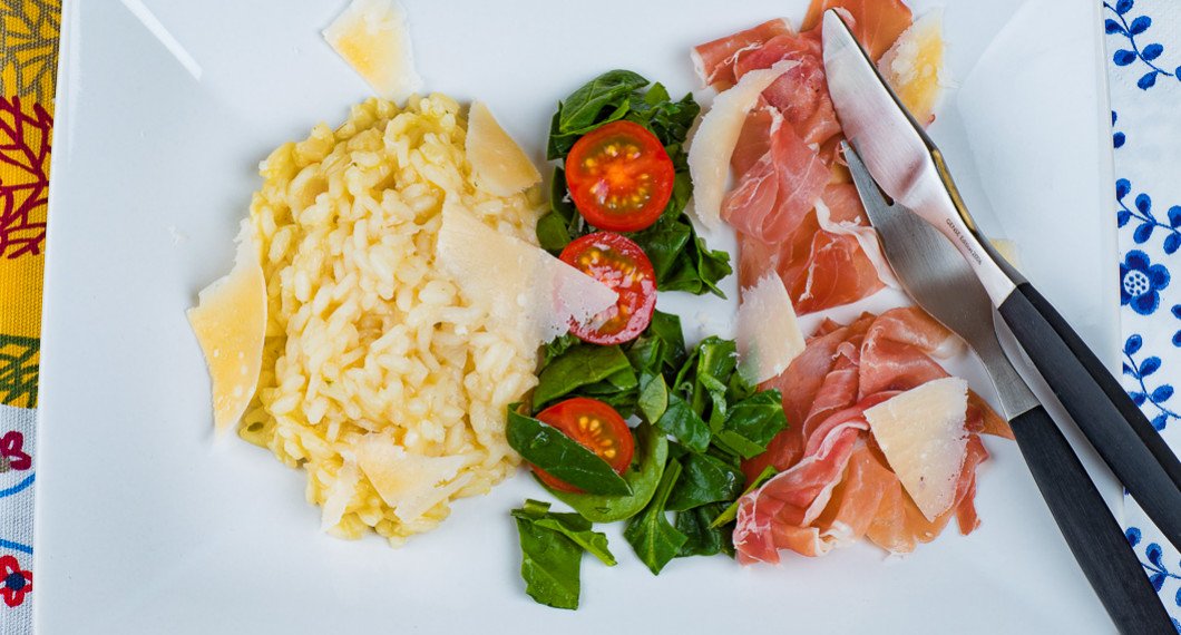 Risotto på tallrik med spenat, tomat och lufttorkad skinka