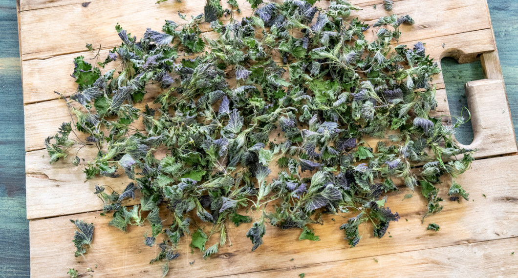 Torkade blad av nässlor på skärbräda