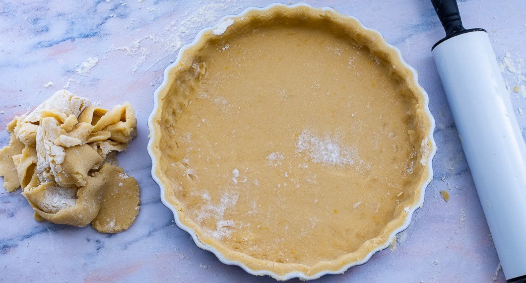 Tryck till degen runt kanterna med kaveln eller skär bort överbliven deg. Spara överbliven deg. 