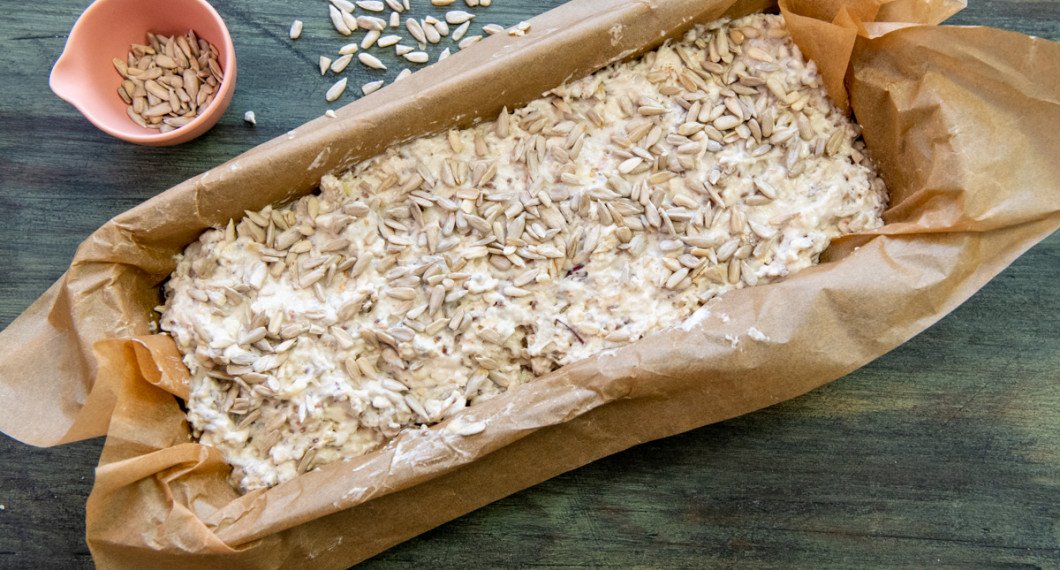 Lägg degen i en brödform med bakplåtspapper. Toppa med solrosfrön. 