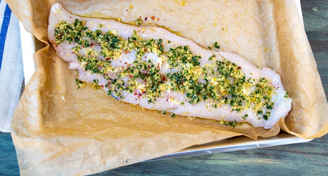 En bit filé av kummel i ugnsformen toppad med ströbrödsblandning redo för ugnen. 