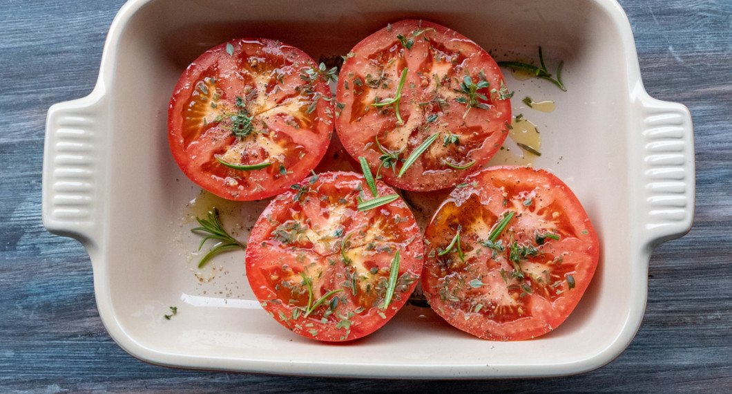Tomathalvorna läggs i en form med olivolja samt saltas och strös över med örter som dragon, timjan och rosmarin.