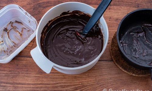 Kolasås rörs ihop med choklad som får smälta och sedan tillsätts mjukt smör till en jämn glasyr eller kräm. 