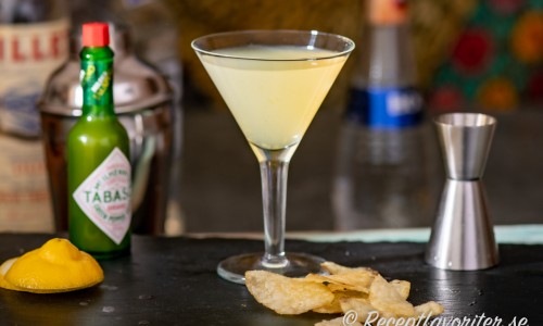 Cocktail med grön tabasco, tequila, vit chokladlikör, Lillet blanc och citron i martiniglas. 