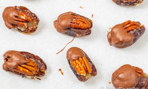 Dadlar med pekannötter doppade i choklad på bakplåtspapper