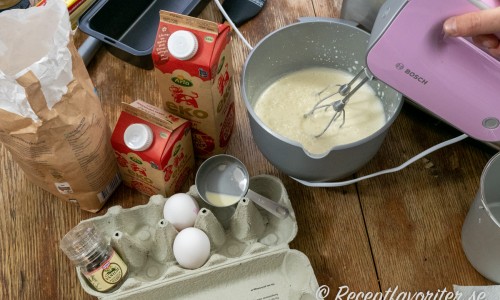 Ingredienser till vaniljglassen - vaniljstång i kvarn, socker, mjölk, grädde och ägg.  