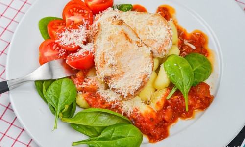 Gnocchi med stekt kycklingfilé och tomatsås samt parmesan på tallrik
