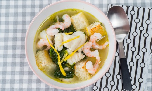 Klar fisksoppa med torsk och räkor i soppskål
