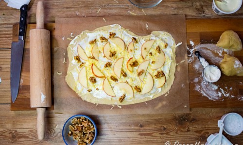 Utkavlad deg till Flammkuchen toppad med crème fraiche, ost, äpple och valnötter. 