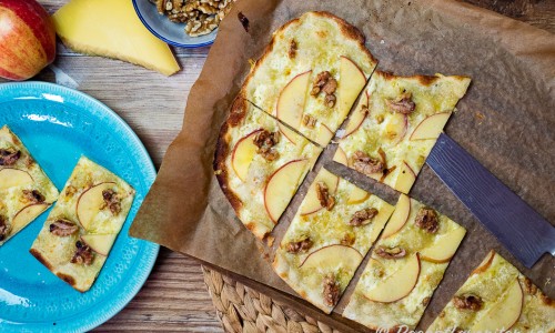 Nybakt Flammkuchen eller Tarte flambée med ost, äpple och valnötter