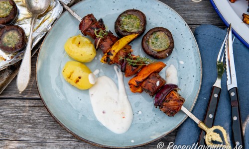 Fläskytterfiléspett med rödlök och paprika serverade med grillad potatis, vitlöksfyllda champinjoner och gräddfilssås med sweet chili. 