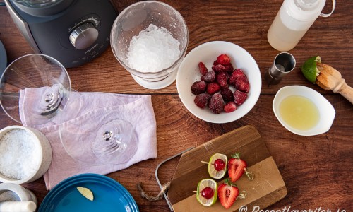 Ingredienser till jordgubbsmargaritan: frysta jordgubbar, limesaft, sockerlag, krossad is och så garnering av lime, cocktailbär och jordgubbshalva på bambupinne. Utanför bild tequila och apelsinlikör. 