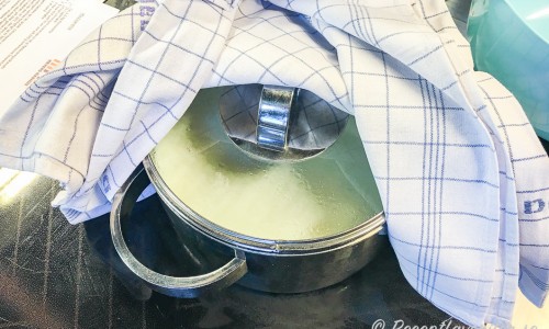 Mjölken står och ystar i kastrull under handduk så den håller värmen. 