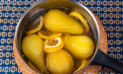 Päronen i sockerlag med ingefära, citron och vanilj i en kastrull. 