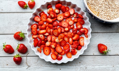 Sköljda och skivade jordgubbar i botten på pajform till pajen. 