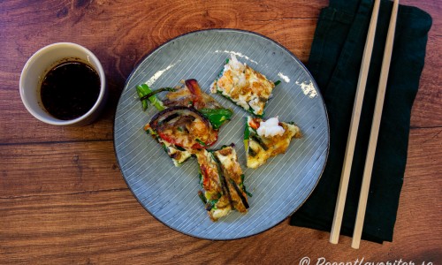 Koreansk matpannkaka med skaldjur och grönsaker serverad med dippsås