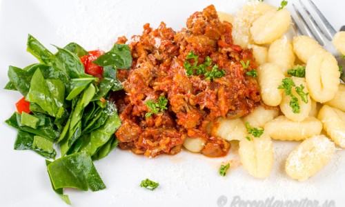 Köttfärssås med lammfärs - här med färsk gnocchi och spenat- och tomatsallad på tallrik.