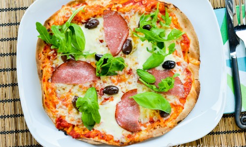 Libapizza med salami, mozzarella och oliver på tallrik
