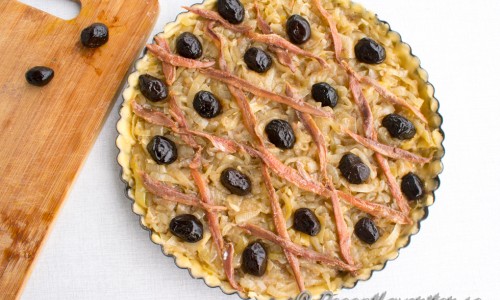 Kavla eller tryck ut pajdegen i en smörad pajform. Fyll med löken och lägg sedan sardeller och oliver i valfritt mönster. Klassiskt är ett rutmönster med sardeller och oliver i rutorna eller kryssen. 