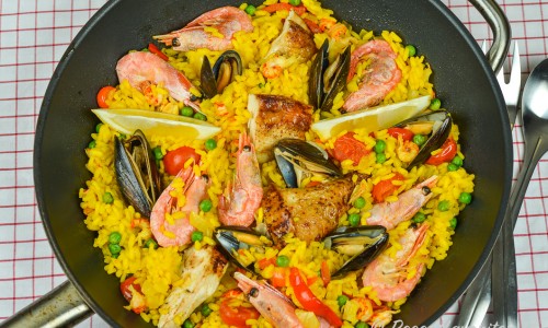 En panna paella med rundkornigt ris och saffran samt kyckling, musslor, räkor, ärtor och tomat.  