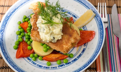 Panerad torsk med serveringförslag av kokt potatis, remoulad, färsk dill, citron, ärtor och röd paprika. 