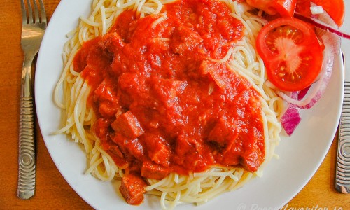 Spagetti Diablo med tomatsås och stark korv och tomatsallad på tallrik