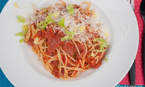 Pasta med tomatsås och salami garnerad med parmesan och hackade blad av stjälkselleri. 