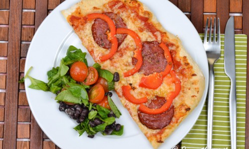 Pizza med salami och röd paprika. 