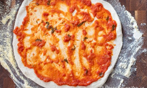 Pizzabottnen toppas med topping efter önskemål som pizzasås, ost med mera. 