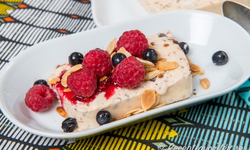 Semifreddo - en italiensk glassdessert garnerade med färska hallon, blåbär och rostad flagad mandel