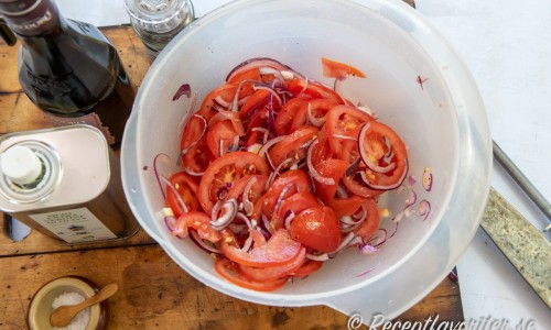 Skiva tomaterna och blanda med rödlöken, olivolja, vinäger samt peppar. 