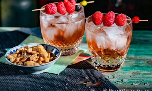 Tranbärsdrinkar med vodka och persikolikör toppade med is och Schweppes Russchian i glas garnerade med färska hallon. 